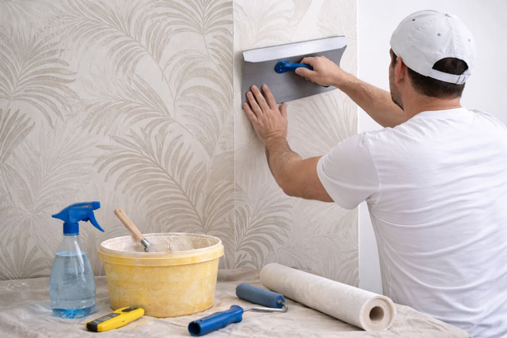 Applicazione carta da parati passo dopo passo con spatola da tappezziere su parete
